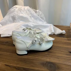 Detalle de zapatos de princesa Lolita para niña con hebilla de perlas y lazo de puntos.