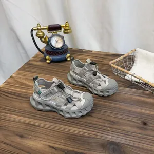 Breathable grey mesh kids' sneakers with protective toe cap on a dark wooden desk