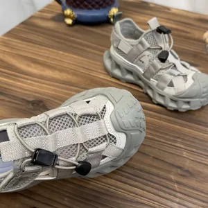 Detail of grey mesh kids' outdoor sandals with toggle lacing system and rugged sole.