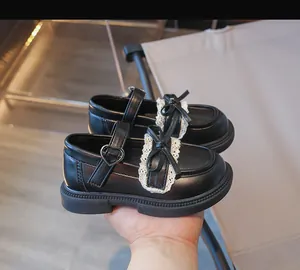 Nahaufnahme von schwarzen Mary Jane Mädchenschuhen mit Spitze und Schleife.