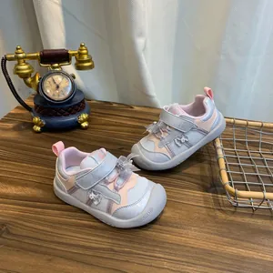 Detailweergave van roze en grijze antislip sportschoenen voor kinderen op houten tafel