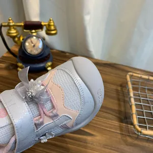 Detailopname van mesh kindersneakers met parelstrik en antislip neuskap in grijs en roze.