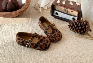Close-up detail of leopard print T-strap baby girl flats in a cozy retro scene setting