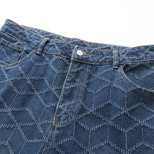 Détail macro montrant le motif en losange texturé sur un jean bleu droit pour homme.