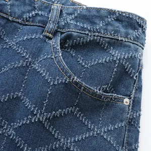 Vue détaillée macro du motif unique en losanges effilochés sur un jean bleu pour homme