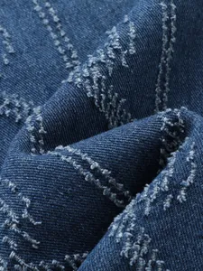 Close-up of distressed fringe detail on blue denim fabric for men's trendy jeans