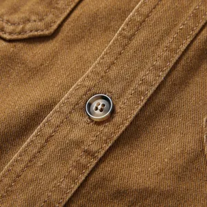 Gros plan sur la texture du chemisier en jean marron avec bouton et surpiqûres