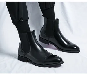 Side view of black pointed-toe Chelsea boots with elastic panels and red soles