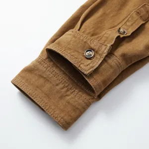 Gros plan du poignet d'une chemise en jean marron pour homme avec tissu texturé.