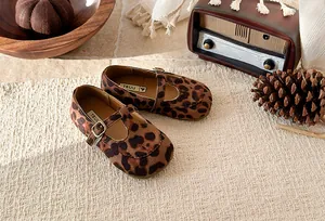 Detailed view of vintage-style girls leopard print T-strap Mary Janes on a textured mat
