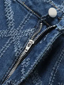 Detail close-up of silver metal zipper and frayed fabric on blue distressed denim jeans.