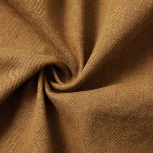 Détail macro d'un tissu denim marron de haute qualité montrant le tissage et les plis.