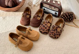Suede T-strap girls' shoes in brown, camel, and leopard print shown in a warm autumn setting
