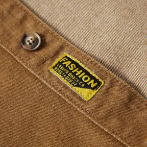 Gros plan de la texture du tissu denim marron avec étiquette de mode et bouton