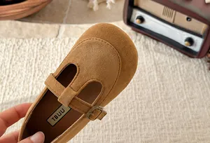 Close-up of tan suede girls' T-strap shoes with square toe and vintage buckle detail