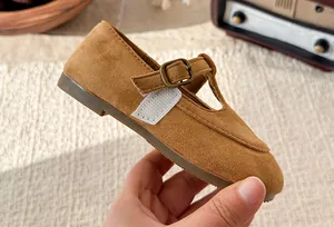 Detailed close-up showing the brown suede texture and metal buckle of girls T-strap shoes