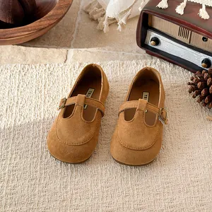 Vintage style girls brown suede T-strap shoes with square toe on a cream woven rug