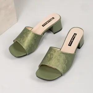 Detail view of green block heel mules with elegant jacquard pattern and square toe design