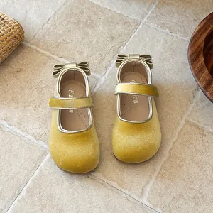 Close-up view of yellow velvet toddler girls' Mary Jane shoes with gold bow detail