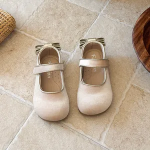 Elegant champagne velvet children's Mary Jane flats featuring a gold bow detail.
