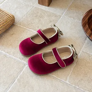 Detailed view of burgundy velvet girls Mary Jane shoes with gold trim and bow detail