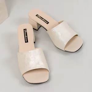 Close-up of elegant cream block heel slides with sophisticated floral jacquard strap