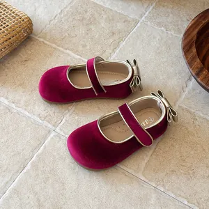 Close-up of burgundy velvet girls' Mary Jane shoes with gold trim and bow detail