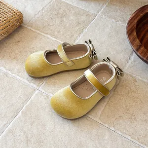 Close-up of yellow velvet girl's Mary Jane shoes with bow detail and soft sole