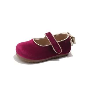 Detail of burgundy velvet girls' princess shoe with a golden bow on the heel