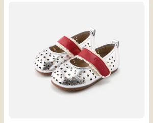 Detail view of silver hollow baby shoes featuring red lace-trimmed Velcro straps