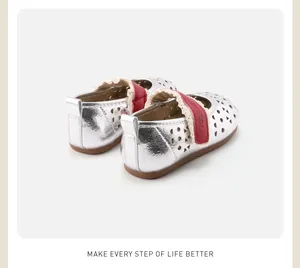 Detail of silver hollow-out toddler shoes with red velcro strap and soft sole