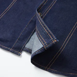 Close-up detail of dark blue denim workwear shirt hem with contrast stitching.