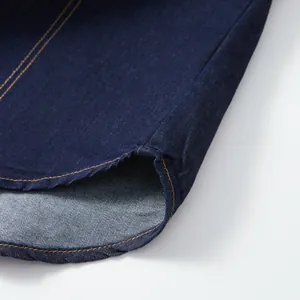 Close-up of the curved hem and durable stitching on a dark blue denim shirt jacket