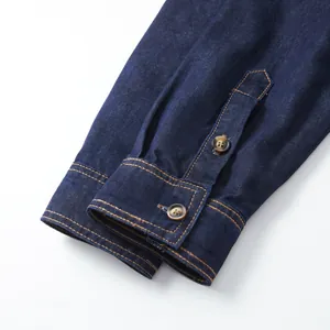 Close-up detail of denim shirt cuff with brown buttons and contrast stitching