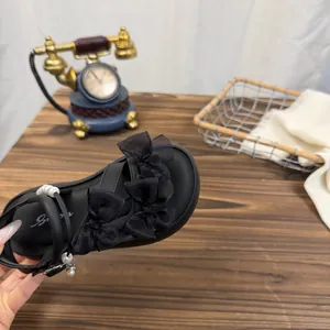 Detail view of girls' black sandals with layered organza bows and pearl accents