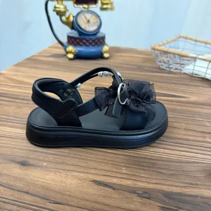 Detail view of girls' black platform sandal with mesh bow and pearl accents