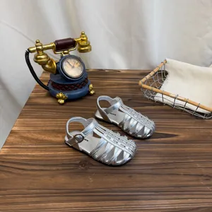 Zijaanzicht van zilveren gevlochten babysandalen met metallic afwerking en gespje.