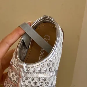 Gros plan de chaussure princesse argentée à paillettes avec bride élastique grise