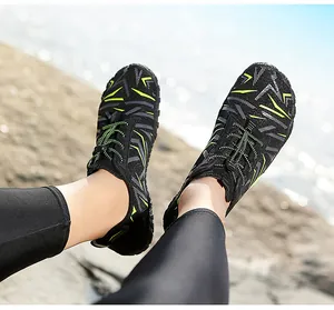Detailed view of quick-dry water shoes with green patterns on a beach background.
