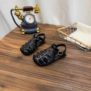 Gedetailleerde weergave van stijlvolle zwarte geweven sandalen met gesloten teen voor meisjes.