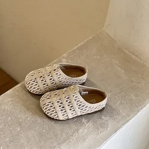 Gros plan de sandales beige tissées et ajourées pour petite fille avec semelle souple