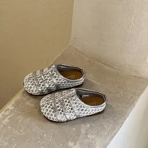 Gros plan sur des sandales pour enfants tressées argentées avec de jolies semelles souples