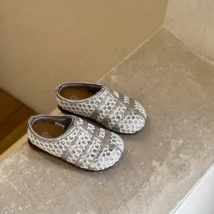 Gros plan de sandales de fille en maille argentée à semelle souple sur pierre texturée