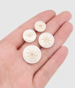 Detailed view of white butterfly shell buttons with gold starburst and crystal center.