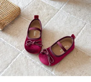 Elegantes zapatos Mary Jane de terciopelo burdeos para niña con lazo sobre suelo piedra