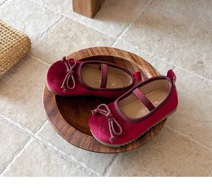 Detalle de merceditas de terciopelo rojo para niña con lazo sobre un plato de madera