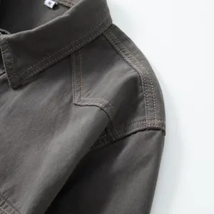 Detailed view of grey cotton denim shirt showing precision shoulder stitching and fabric texture