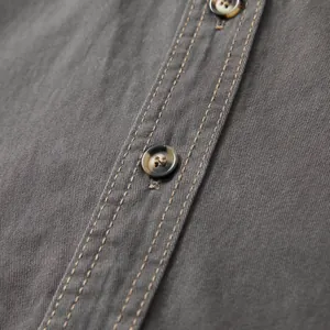 Close-up macro detail of a men's cotton shirt showing button and contrast stitching