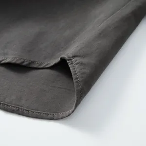 Detailed macro shot showing high-quality stitching on a dark gray cotton denim shirt hem