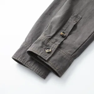 Macro view showing the high-quality stitching and button detail on a grey shirt cuff